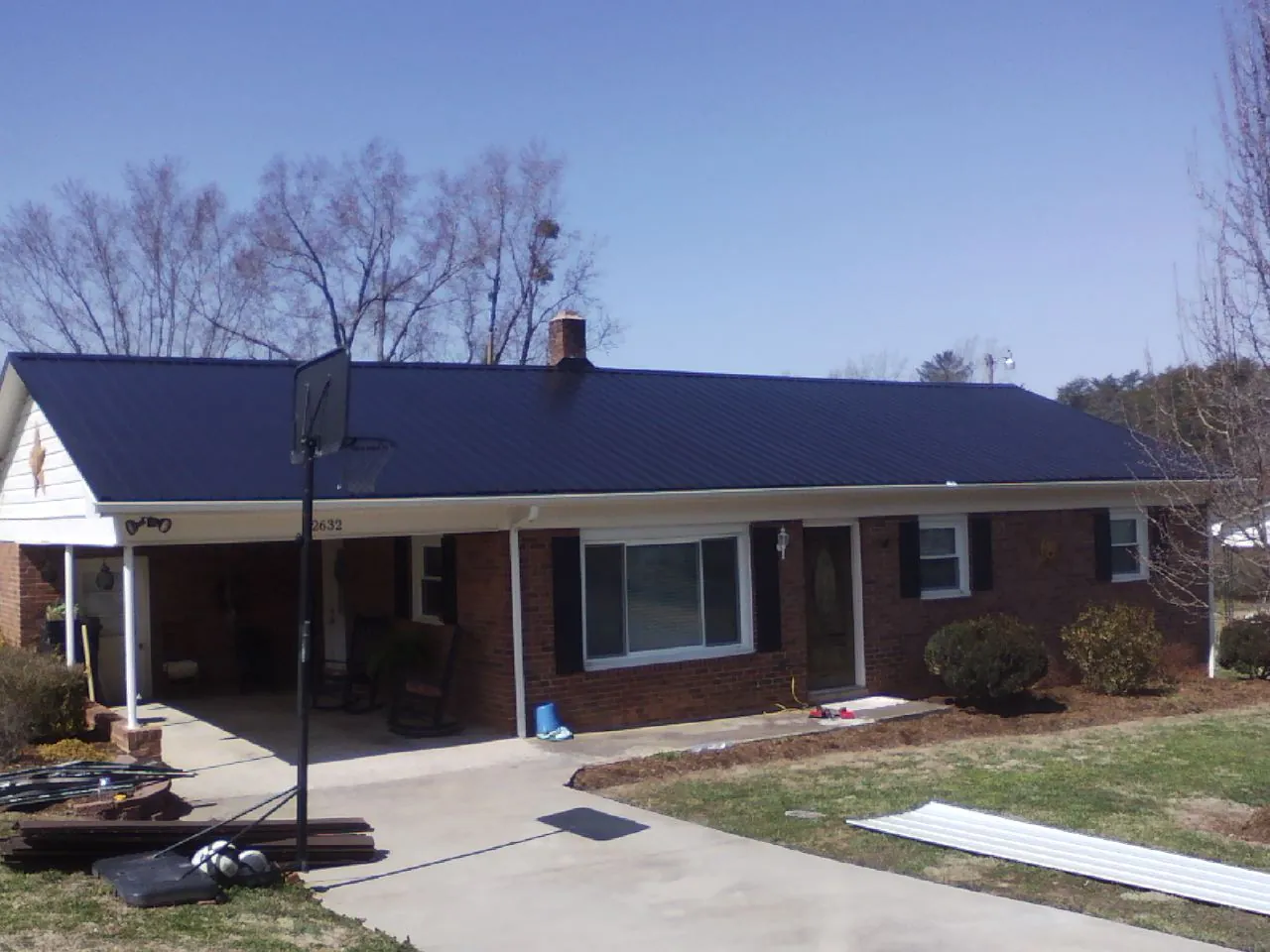 Finished dark blue metal roof on a brick ranch with a carport in Danville